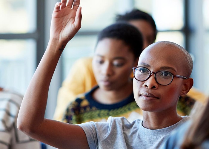 A student raises their hand in glass while other students look on.
